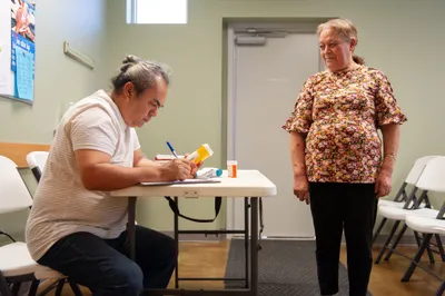 Volunteer Eddie Garcia, left, takes down prescription information for Sanjuana Dominguez at a medical clinic provided free of charge to local residents in Hope, Ark. on Sept. 7, 2023. Photo by Rory Doyle.